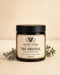 The Original Unscented Tallow Balm in an amber glass jar with black lid, surrounded by thyme sprigs